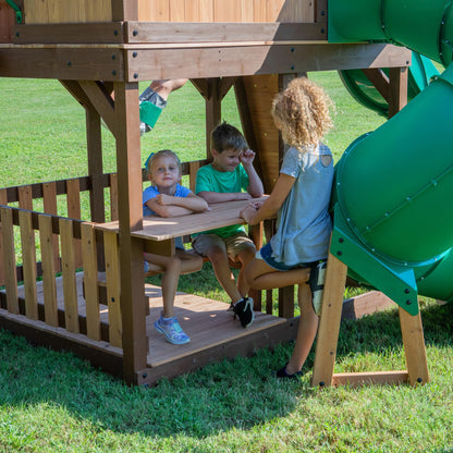 Backyard Discovery Skyfort All Cedar Swing Set, Elevated Covered Wood Roof Clubhouse with Bay Windows, 2 Belt Swings, Web Swing, 10ft Wave Slide, 5 ft Tube Slide, Covered Picnic Table, 5 ft Rock Wall